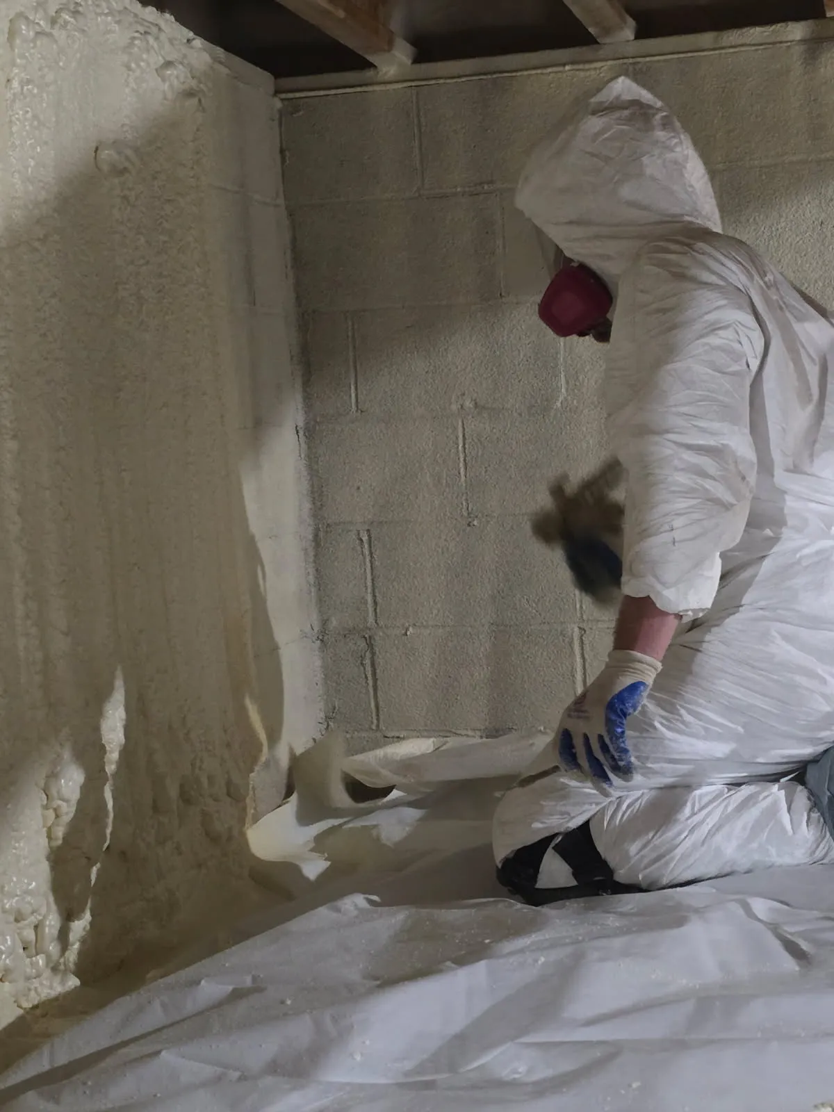Close-up of worker applying foam to block wall floor corner